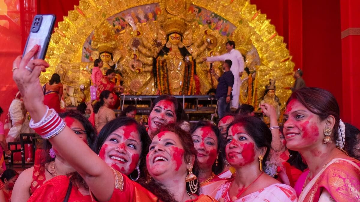 <div class="paragraphs"><p>Women take selfies with Goddess Durga's idol during Durga Puja festival, in Gurugram.</p></div>