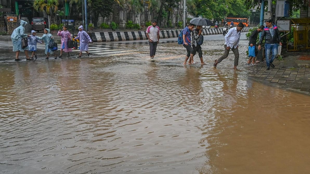 <div class="paragraphs"><p>Children and People walk in Rain water logging on the road at Anil Kumble Circle in Bengaluru on Tuesday.</p></div>