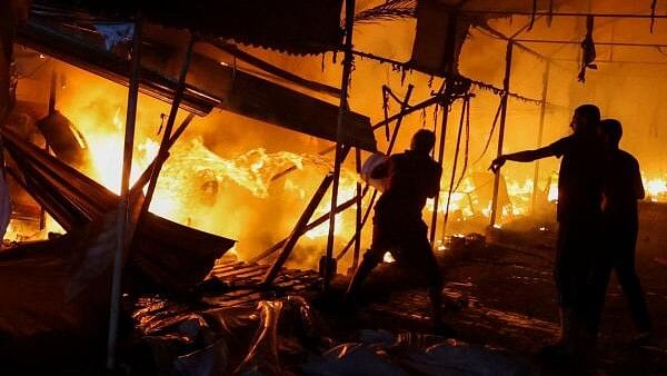 <div class="paragraphs"><p>People attempt to extinguish a fire at the site of an Israeli strike on tents sheltering displaced people at Al-Aqsa hospital, where Palestinian Shaban al-Dalou was burnt to death, in Deir Al-Balah in the central Gaza Strip, October 14, 2024.</p></div>