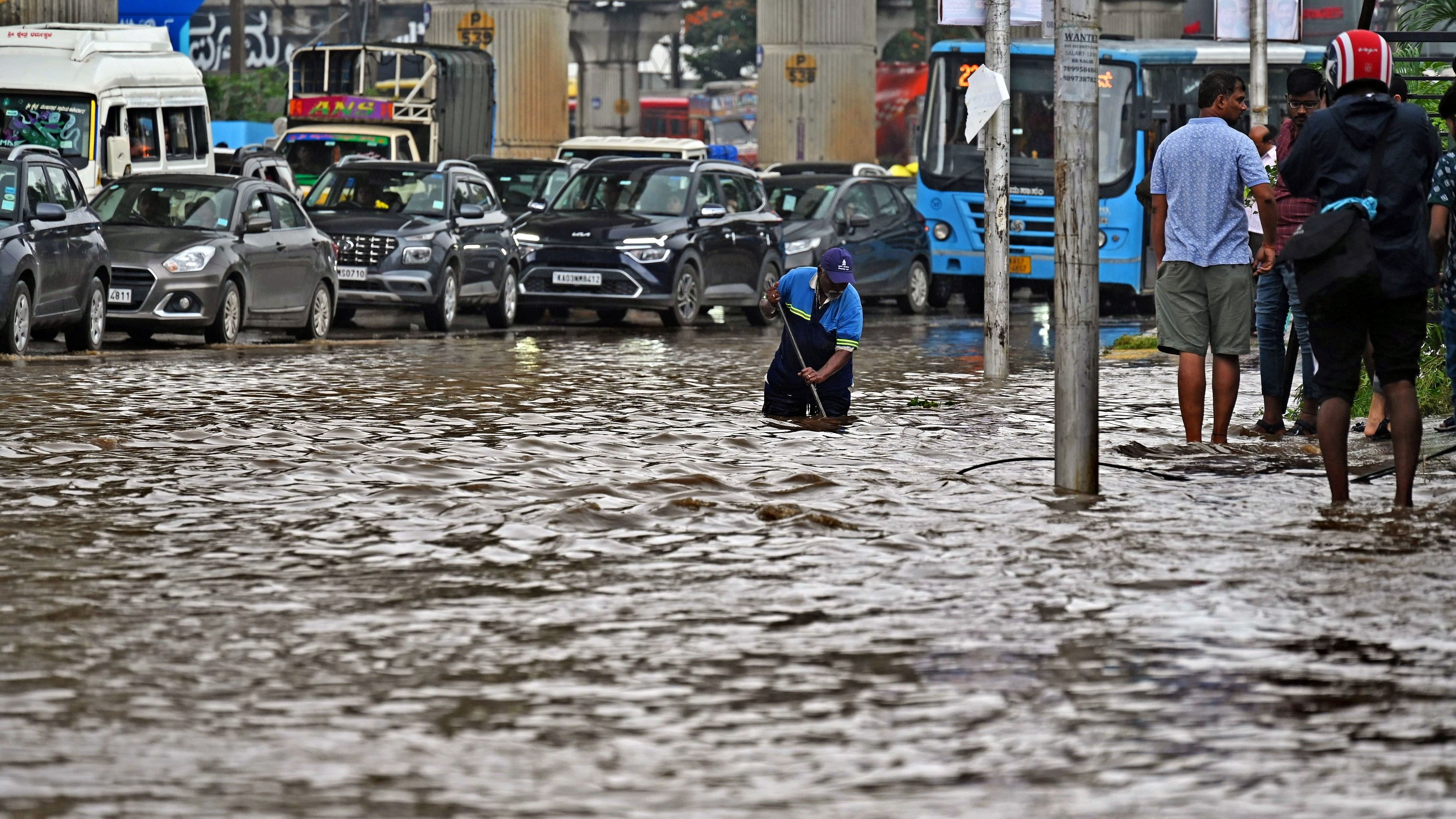 <div class="paragraphs"><p>A BBMP worker clears a blocked drain at a waterlogged stretch on Mysuru Road on Sunday. </p></div>