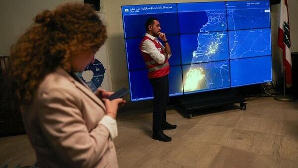 <div class="paragraphs"><p>A Red Cross member from the Disaster Risk Reduction (DRR) unit stands near a screen showing a map of Israel's airstrikes on Lebanon, during an interview with Reuters at the government palace in Beirut, Lebanon October 22, 2024.</p></div>