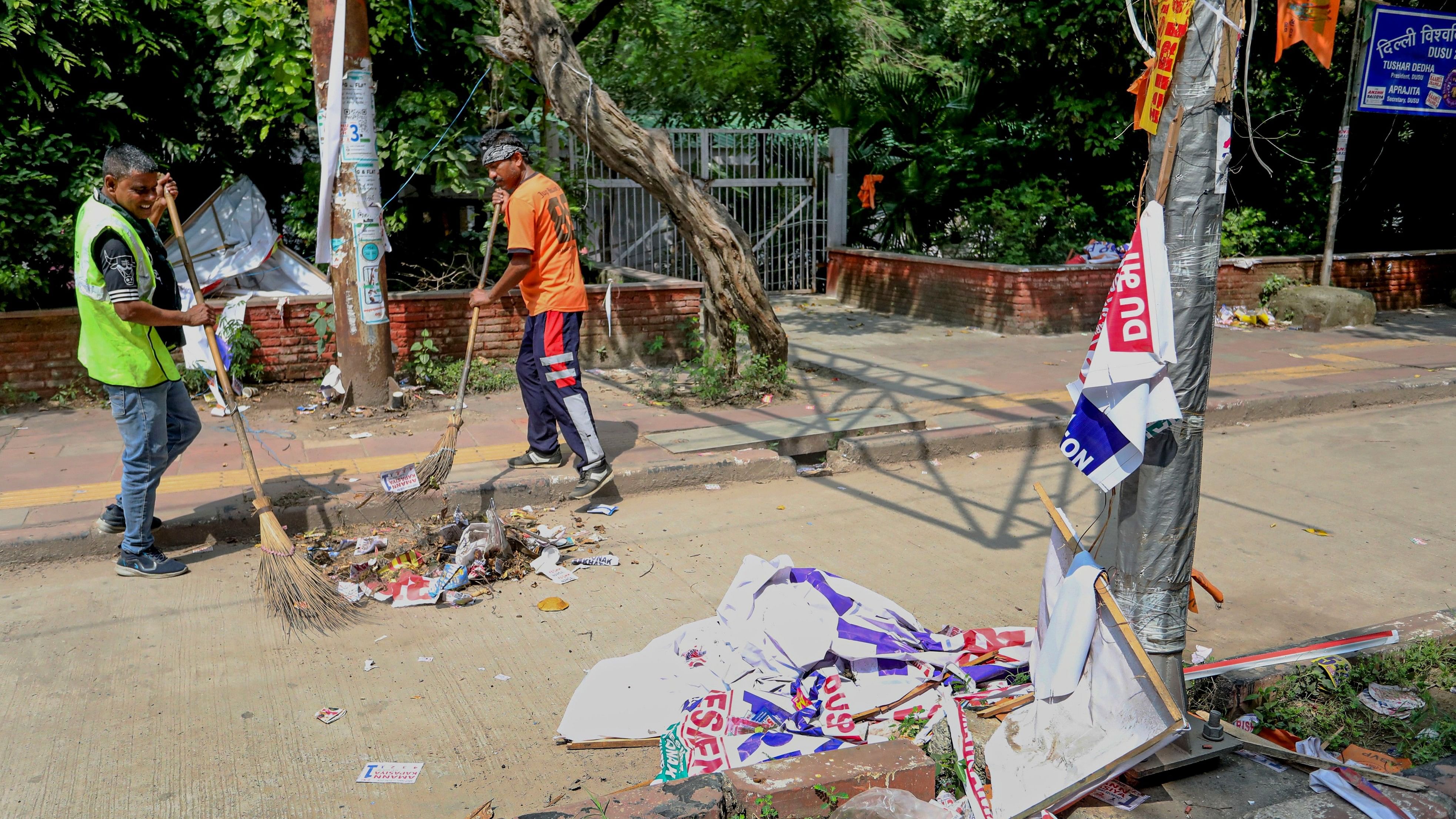 <div class="paragraphs"><p>Workers clear banners and posters from an area after the DUSU polls on September 28. </p></div>