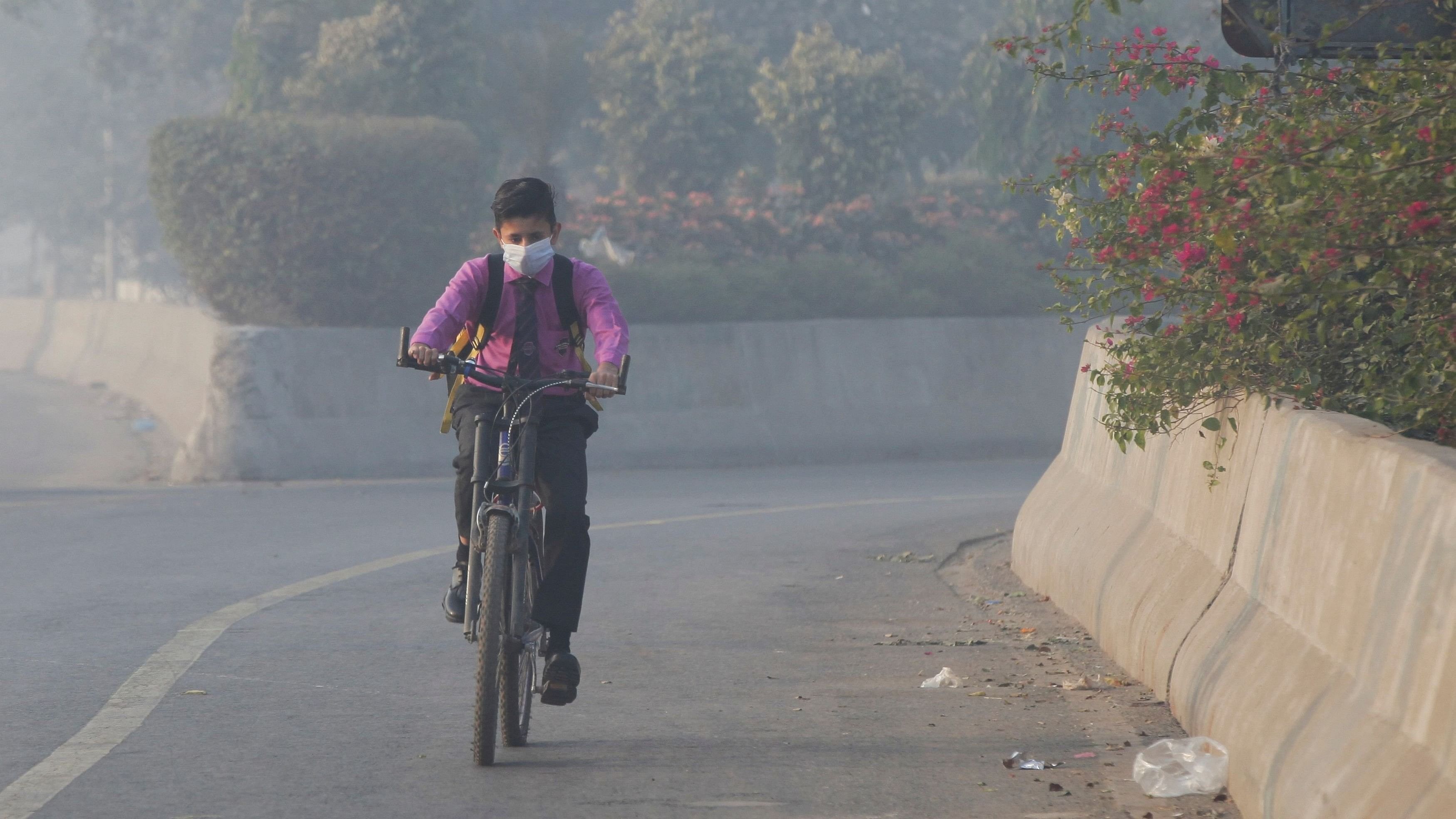 FILE PHOTO: Student rides a bicycle to school amid dense smog in Lahore, Pakistan November 24, 2021. REUTERS/Mohsin Raza/File Photo