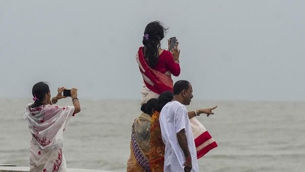 <div class="paragraphs"><p>Visitors take pictures at a beach at Digha ahead of the landfall of Cyclone 'Dana', in Purba Medinipur district, West Bengal, Thursday.</p></div>