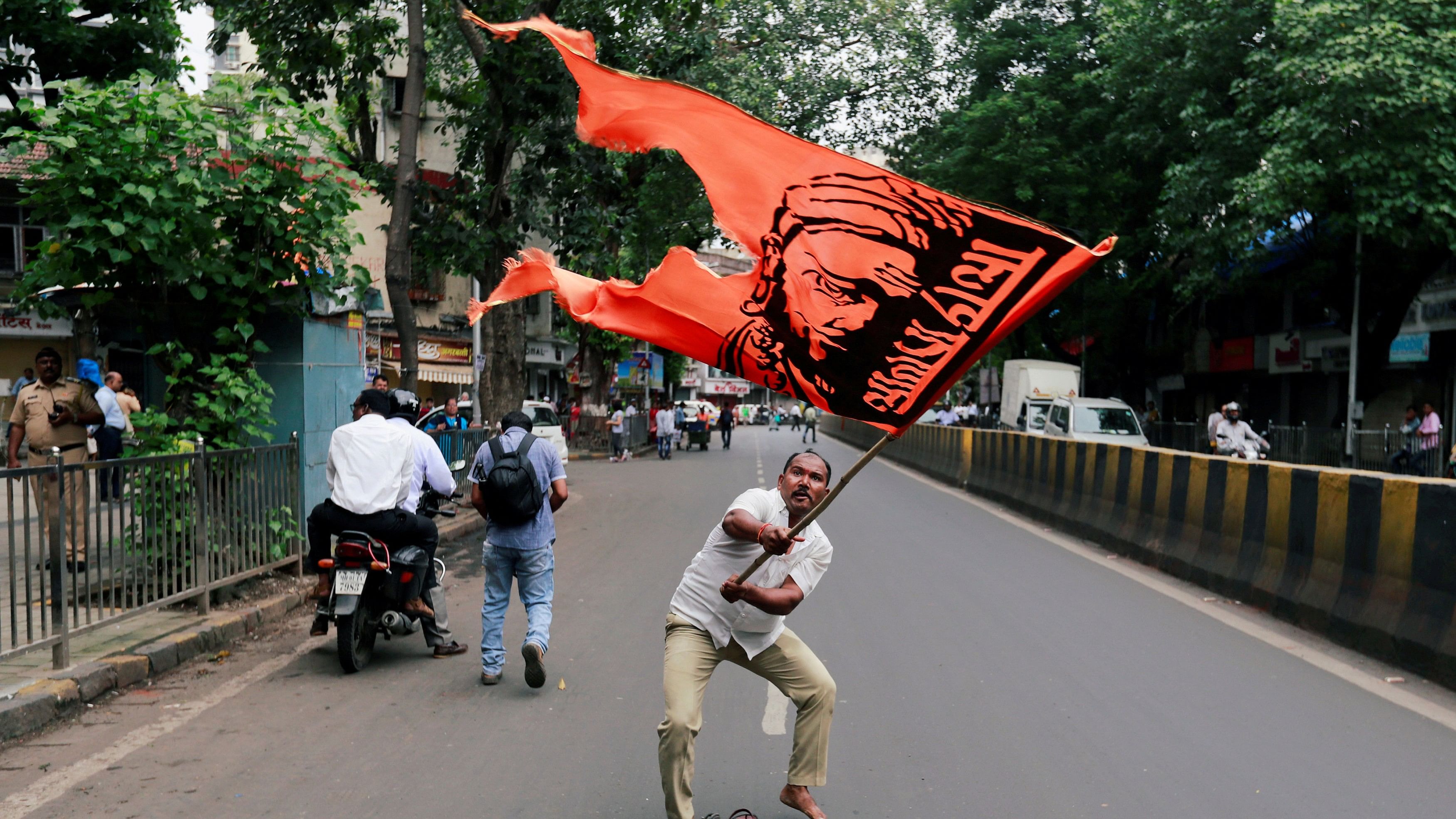 <div class="paragraphs"><p>In this file photo, a man waves a flag as he blocks a road during a protest, organised by Maharashtra state's Maratha community, to press their demands for reserved quotas.</p></div>