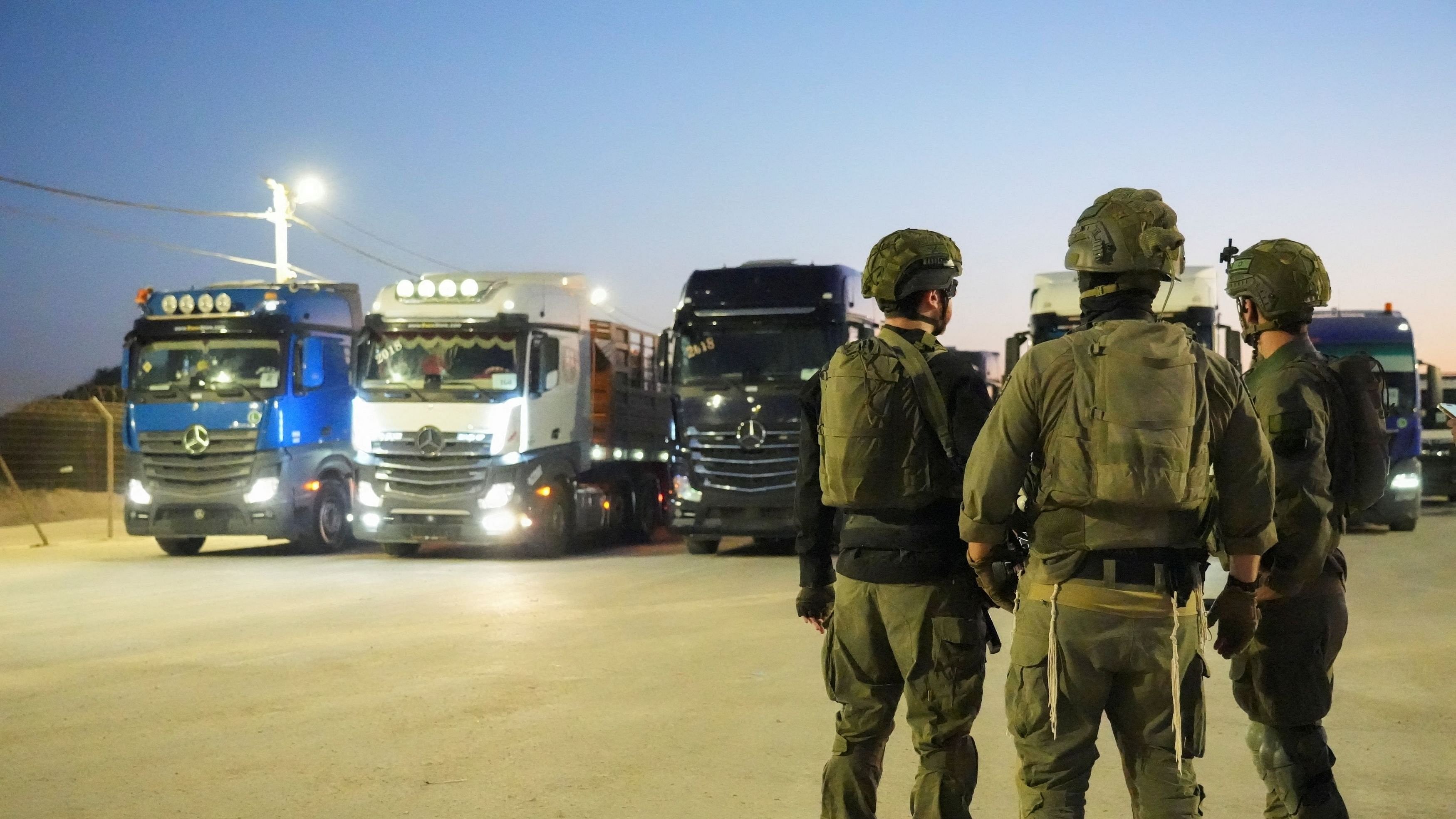 <div class="paragraphs"><p>Israeli soldiers stand near trucks carrying humanitarian aid that wait before making their way to the Gaza Strip.</p></div>