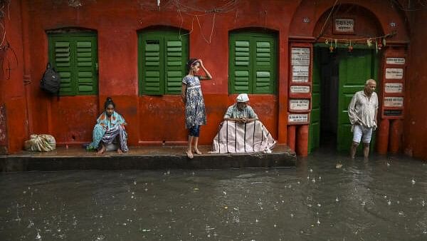 <div class="paragraphs"><p>People take shelter during rain in the aftermath of cyclone 'Dana', in Kolkata, Friday.&nbsp;</p></div>