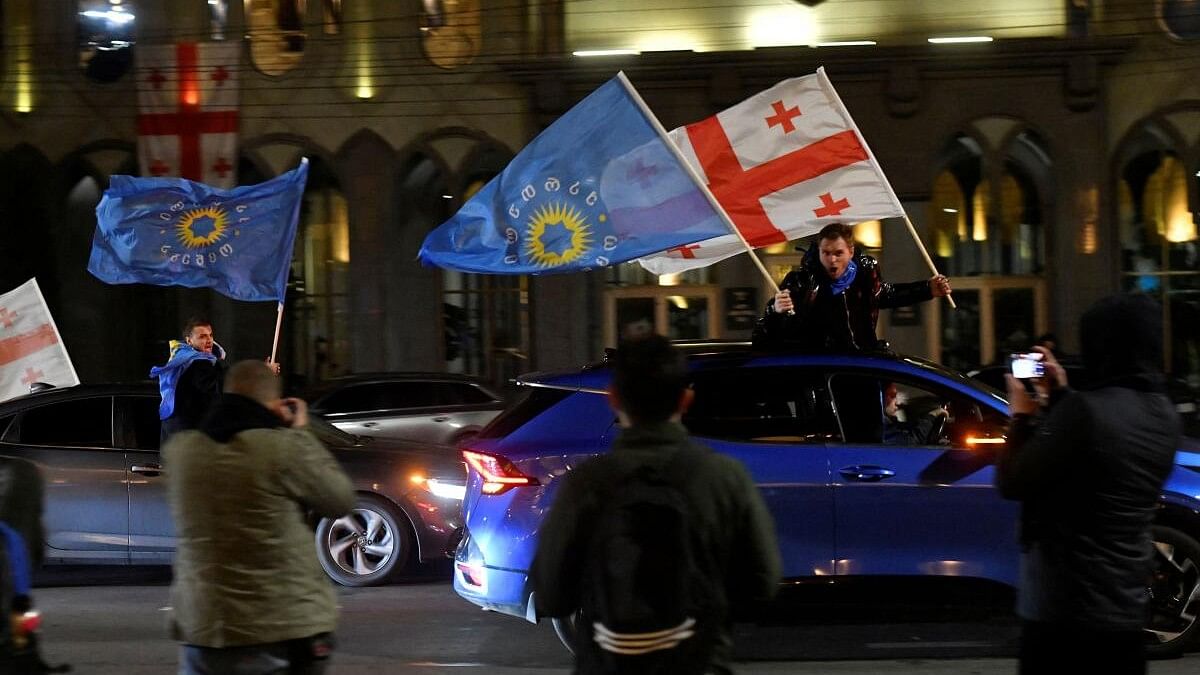 <div class="paragraphs"><p>Supporters of the Georgian Dream party wave Georgian flags and the party's flags from cars after the announcement of exit poll results in parliamentary elections, in Tbilisi, Georgia.</p></div>