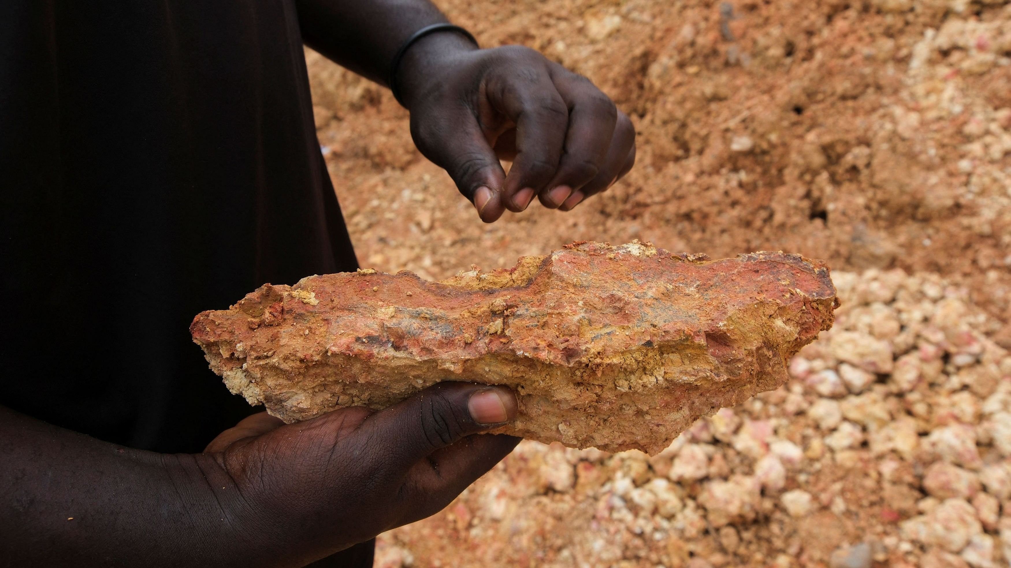 An illegal artisanal miner inspects an excavated rock for traces of gold at the Prestea-Huni Valley Municipal District in the Western Region, Ghana August 17, 2024. REUTERS/Francis Kokoroko