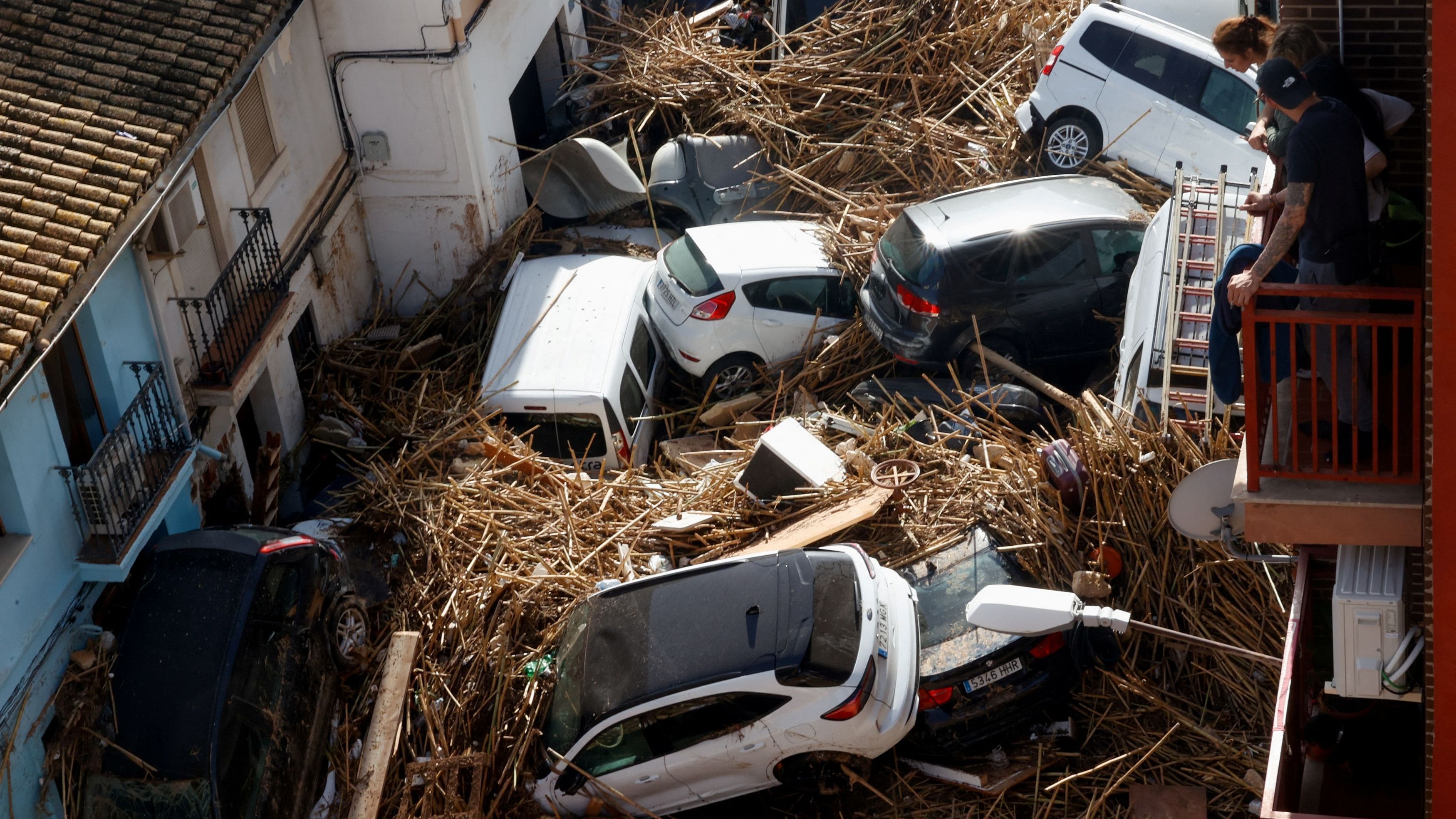 <div class="paragraphs"><p>People look from a balcony at a street with piled up cars in the aftermath of torrential rains that caused flooding, in Paiporta, Spain, October 31, 2024.</p></div>