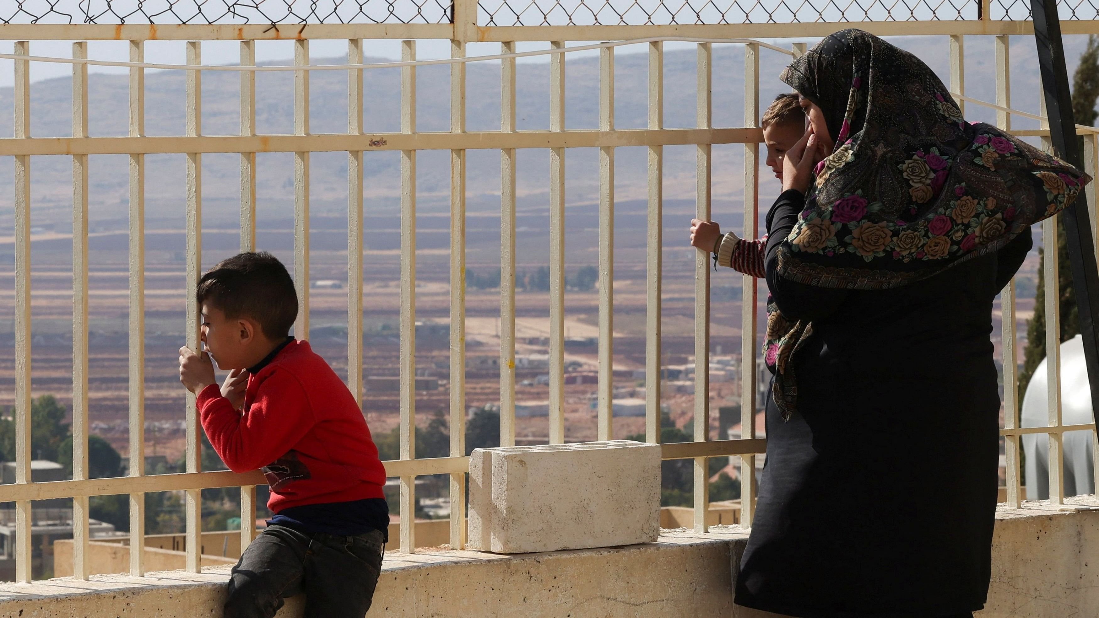 <div class="paragraphs"><p>Displaced people look out from behind a fence at a school turned into a shelter housing displaced people who fled from Baalbek and surrounding areas, in the mountainous Christian town of Deir al-Ahmar in eastern Lebanon </p></div>