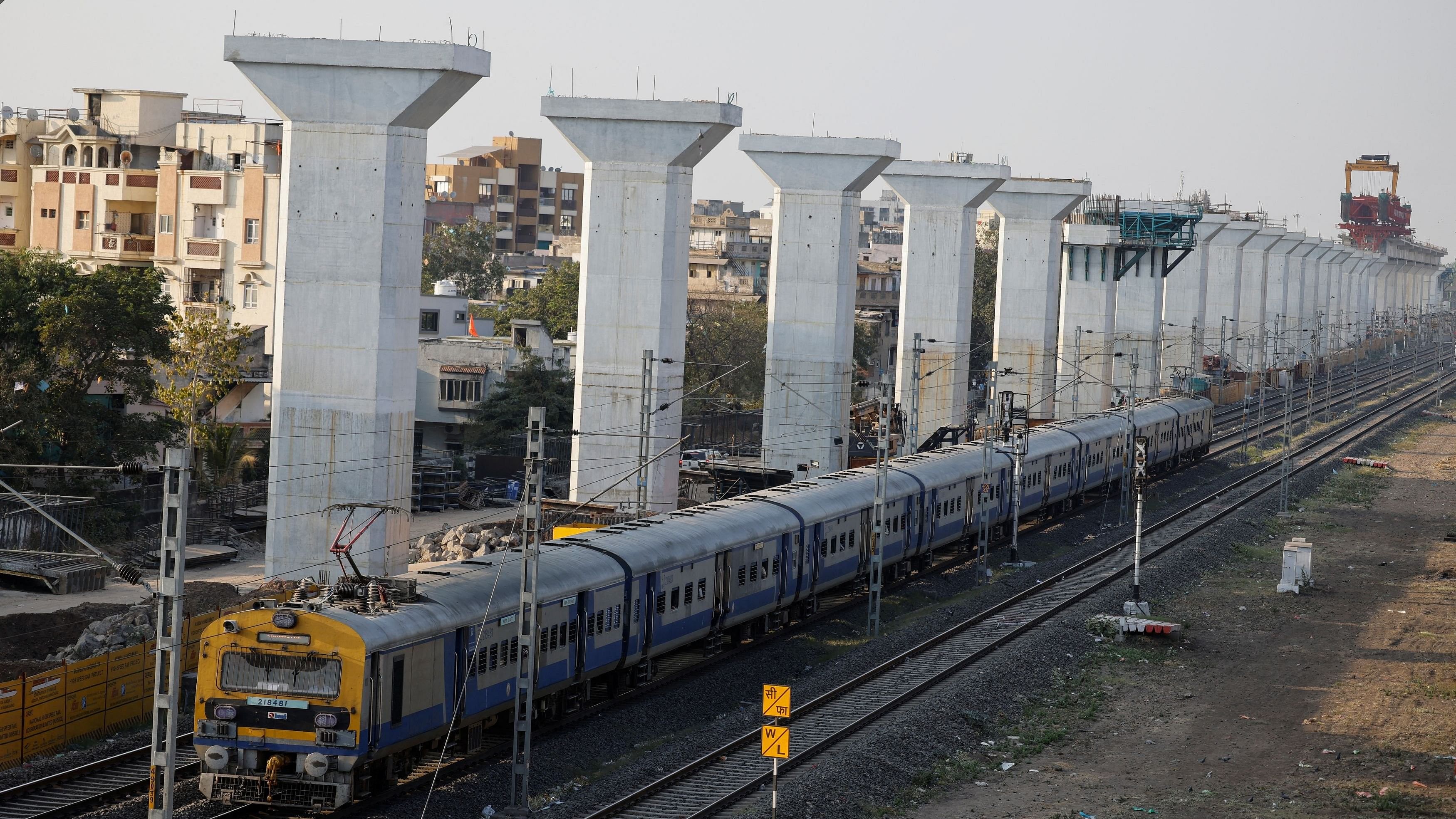 <div class="paragraphs"><p>File photo of a passenger train moves past the under-construction elevated corridor of the Ahmedabad-Mumbai bullet train on the outskirts of Ahmedabad.</p></div>