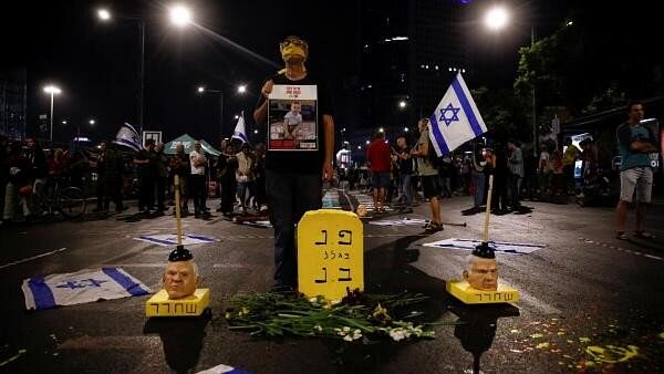 <div class="paragraphs"><p>A protester holds a sign next to a mock grave reading "Buried here because of Benjamin Netanyahu" and masks representing Israeli Prime Minister Benjamin Netanyahu with plungers on them, as people attend a demonstration against Netanyahu's government and demand a deal to release all hostages held in Gaza, amid the Israel-Hamas conflict, in Tel Aviv, Israel November 2, 2024.</p></div>