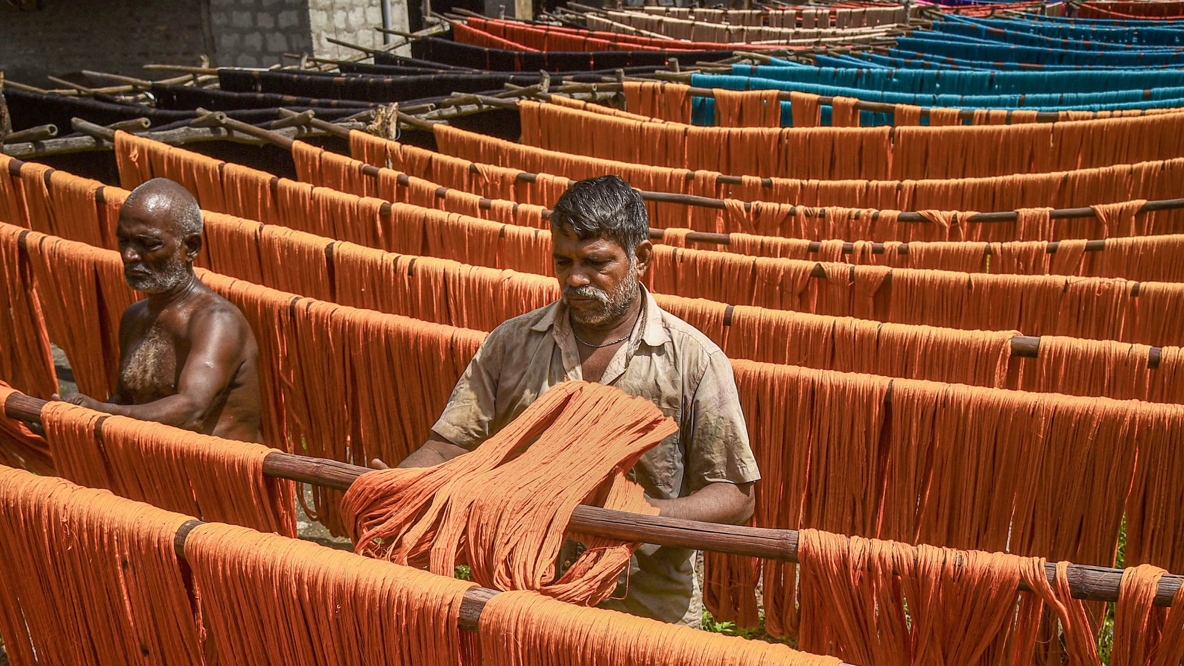 <div class="paragraphs"><p>Workers hang dyed yarn for drying under the sun at a textile mill, in Guntur district.</p></div>