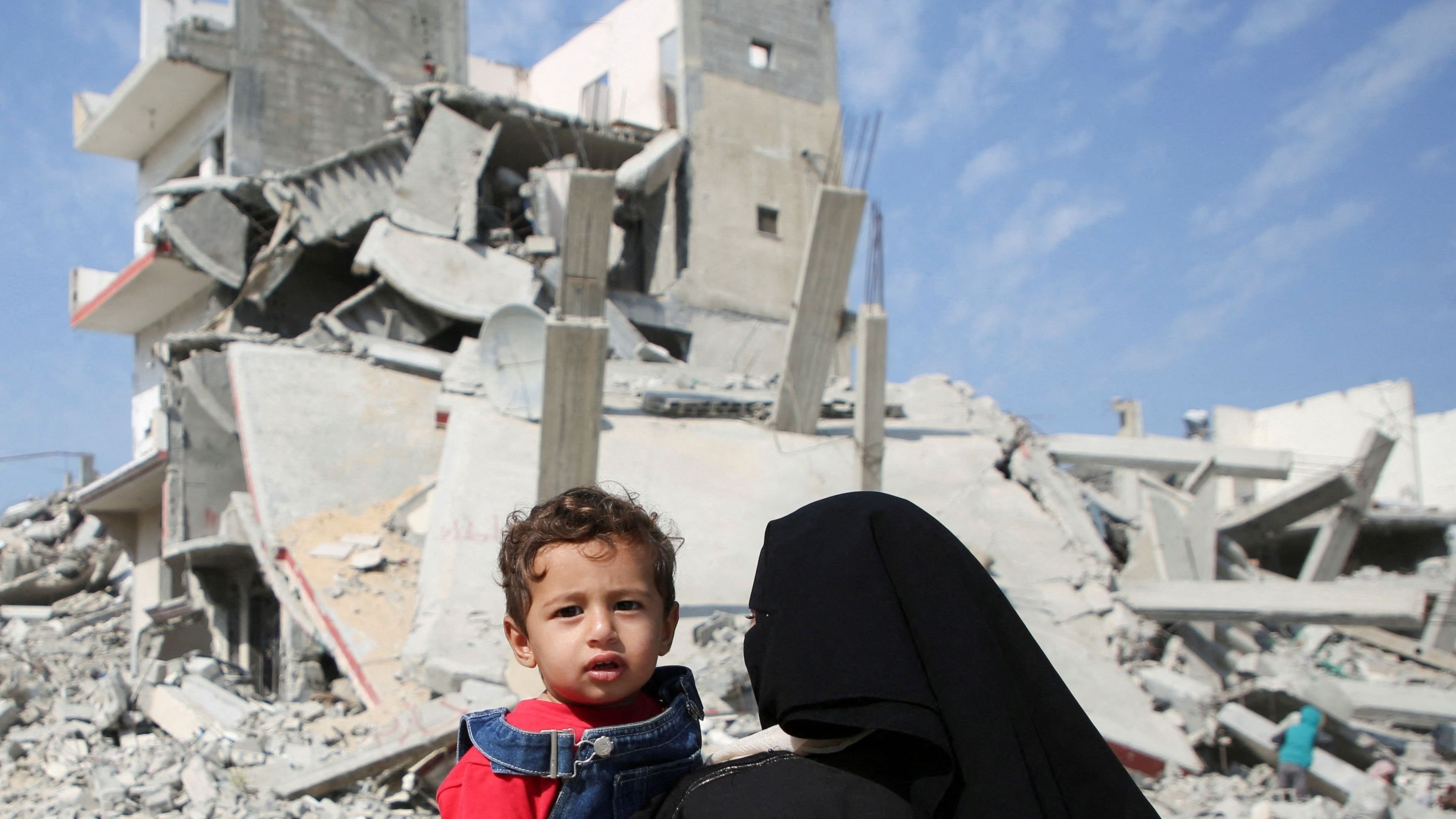 <div class="paragraphs"><p>A Palestinian woman carries a child as they walk past the rubble of houses destroyed in previous strikes during the Israeli military offensive, amid the Israel-Hamas conflict, in Khan Younis in the southern Gaza Strip.</p></div>