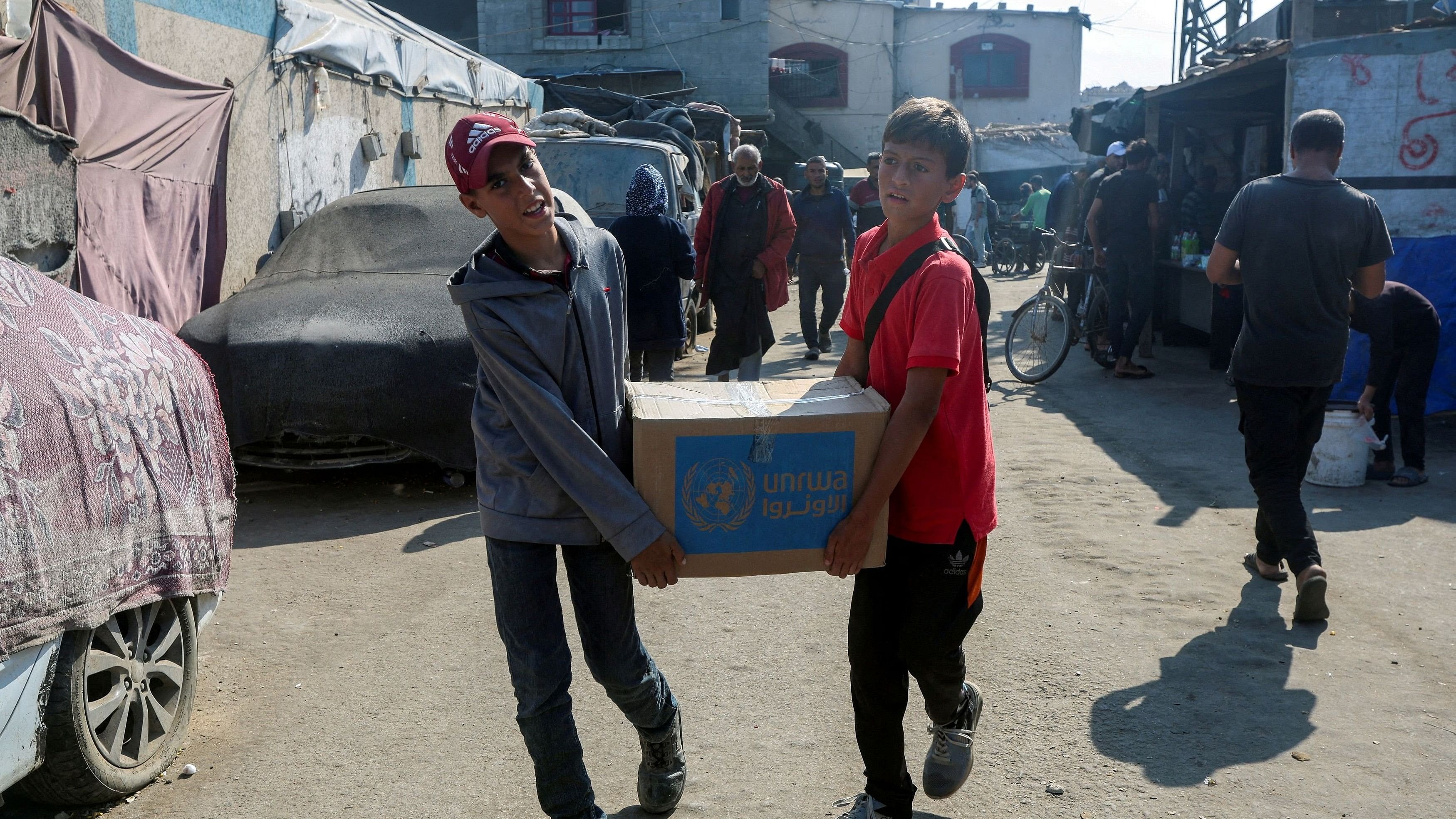 <div class="paragraphs"><p>Palestinians carry an aid box distributed by the United Nations Relief and Works Agency in Deir Al-Balah, central Gaza Strip.&nbsp;</p></div>