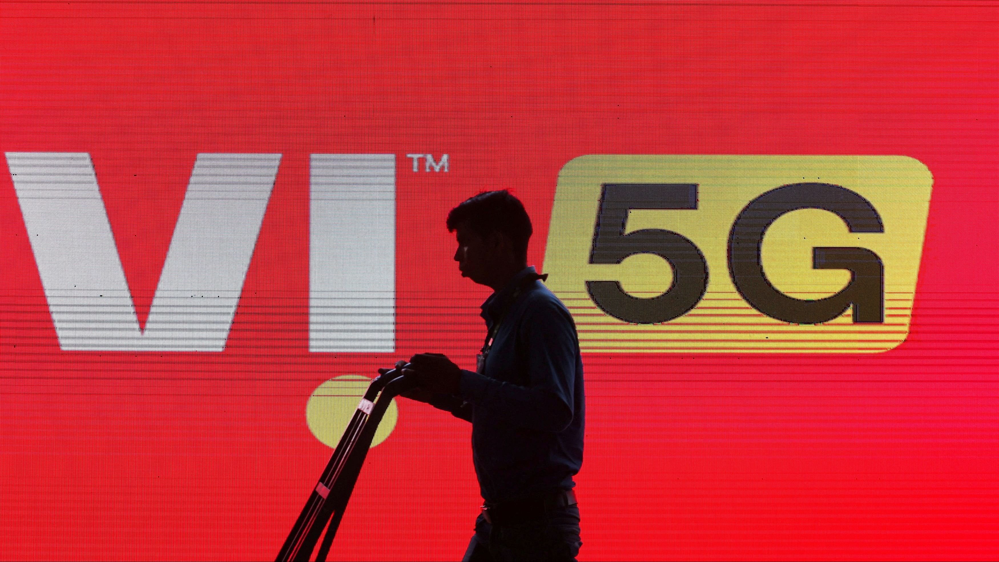 <div class="paragraphs"><p> A man walks across the LED display board showing the logo of Vodafone-Idea.</p></div>