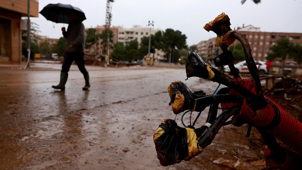 <div class="paragraphs"><p>A man carrying an umbrella walks on a muddied road past electricity cables following catastrophic flooding in Spain.</p></div>