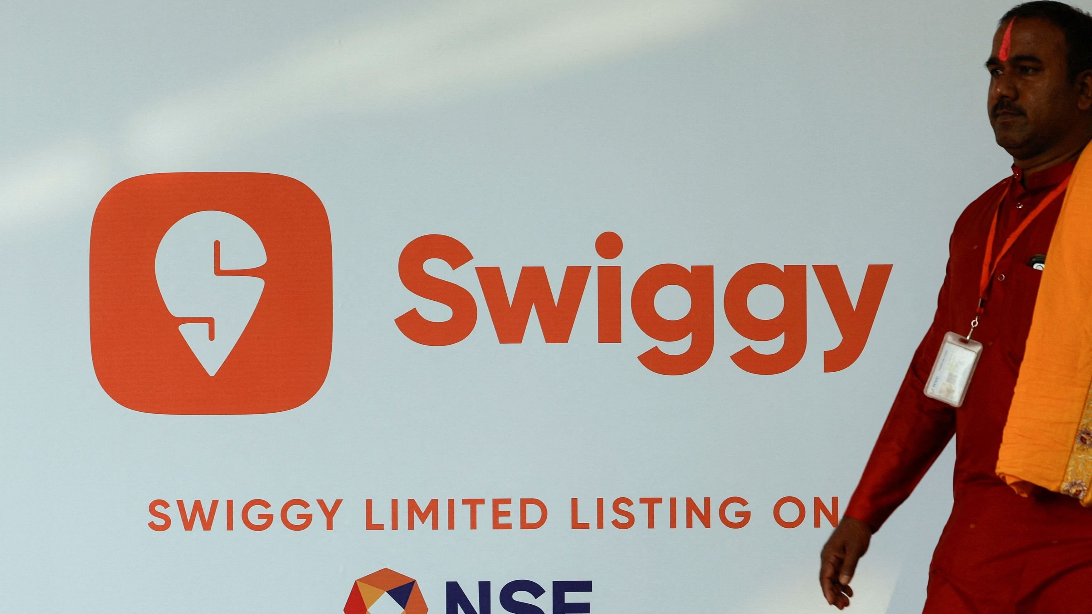 <div class="paragraphs"><p>A priest walks past a logo of Swiggy ahead of its Initial Public Offering  in Mumbai.</p></div>