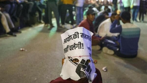 <div class="paragraphs"><p>A civil services aspirant wears a poster as a mask during a protest against the decision of the Uttar Pradesh Public Service Commission (UPPSC) to conduct the Provincial Civil Services (PCS), Review Officer (RO) and Assistant Review Officer (ARO) preliminary examinations in two days, in Prayagraj, Thursday, Nov. 14, 2024.</p></div>