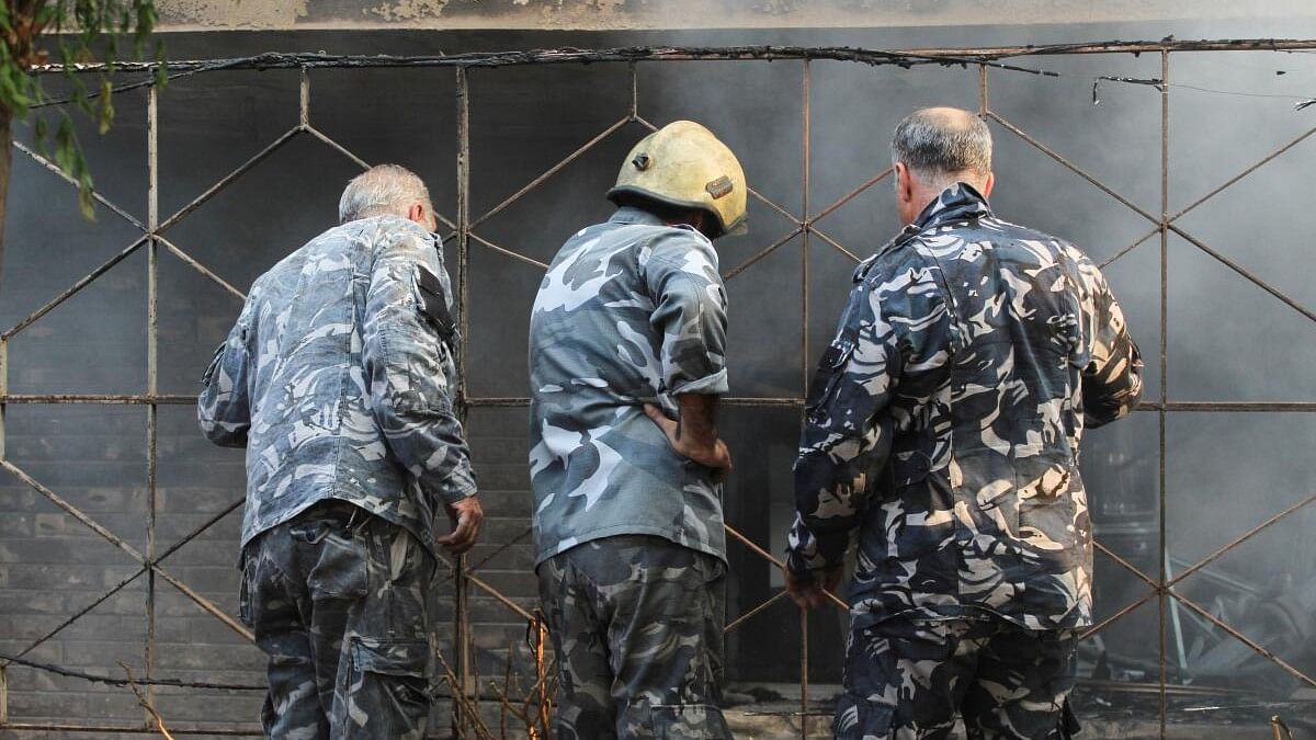 <div class="paragraphs"><p>Syrian civil defence officers stand at a damaged site after what the Syrian state news agency said was an Israeli strike in the Damascus suburb of Mazzeh, Syria.</p></div>