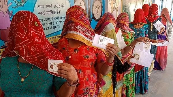 <div class="paragraphs"><p>Women show their identification cards as they wait in a queue to cast their votes.</p></div>