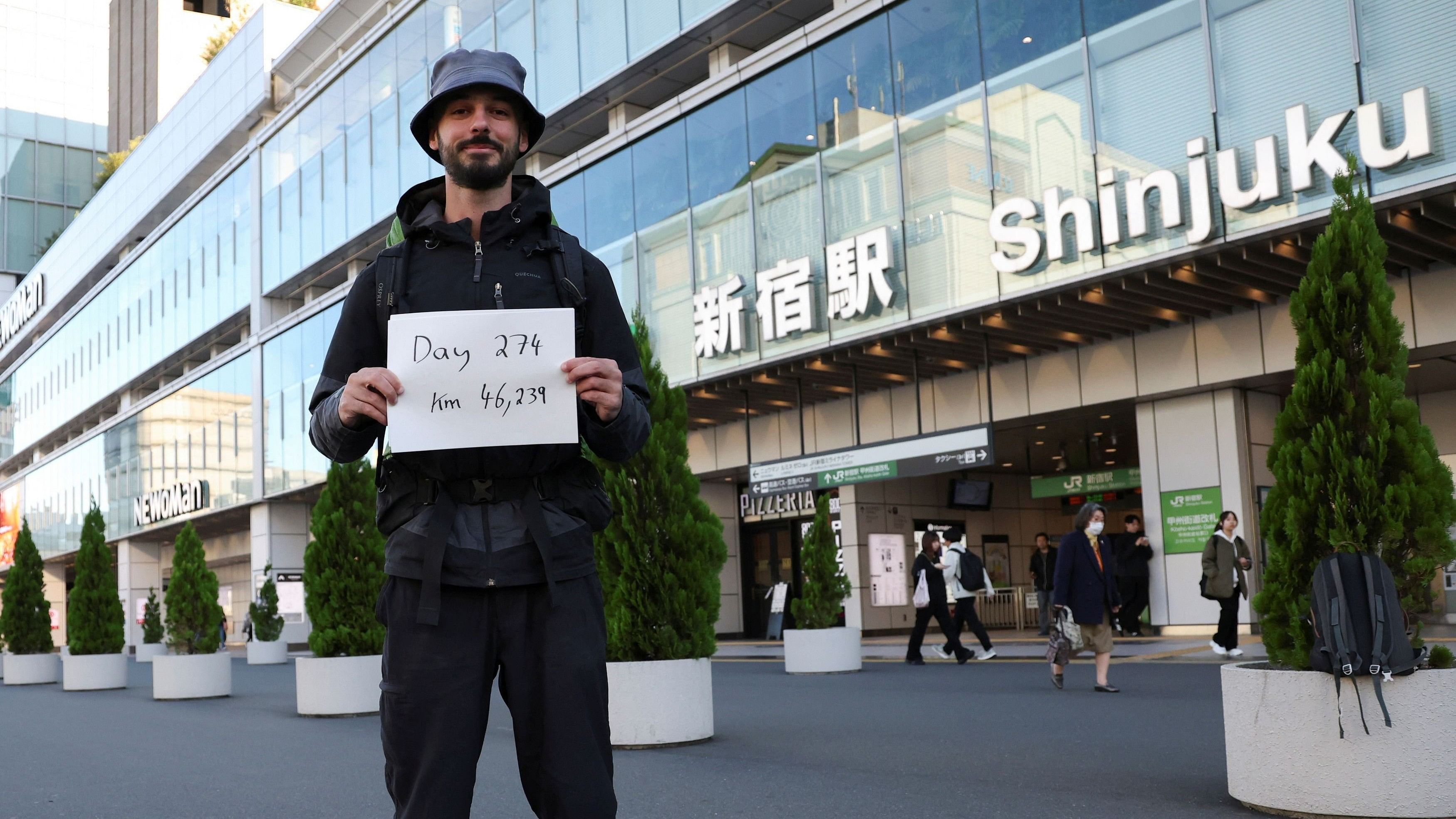 <div class="paragraphs"><p>Omar Nok, a 30-year-old Egyptian who travelled from Cairo to Tokyo, holds a sign noting the days and distance he has travelled, in front of Shinjuku station in Tokyo, Japan, November 7, 2024. </p></div>