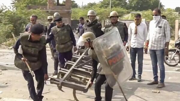 <div class="paragraphs"><p>Police personnel remove tractor plows after supporters of independent candidate Naresh Meena blocked a road</p></div>