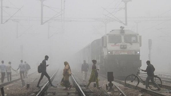 <div class="paragraphs"><p>Commuters cross railway tracks amid fog, in Gurugram on Wednesday.</p></div>