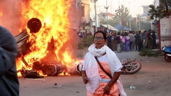 <div class="paragraphs"><p>A woman passes by burning vehicles during demonstrations after three bodies, suspected to be of six missing persons from Jiribam district, were found near the Manipur-Assam border on Friday night, in Imphal, Saturday, Nov. 16, 2024.</p></div>