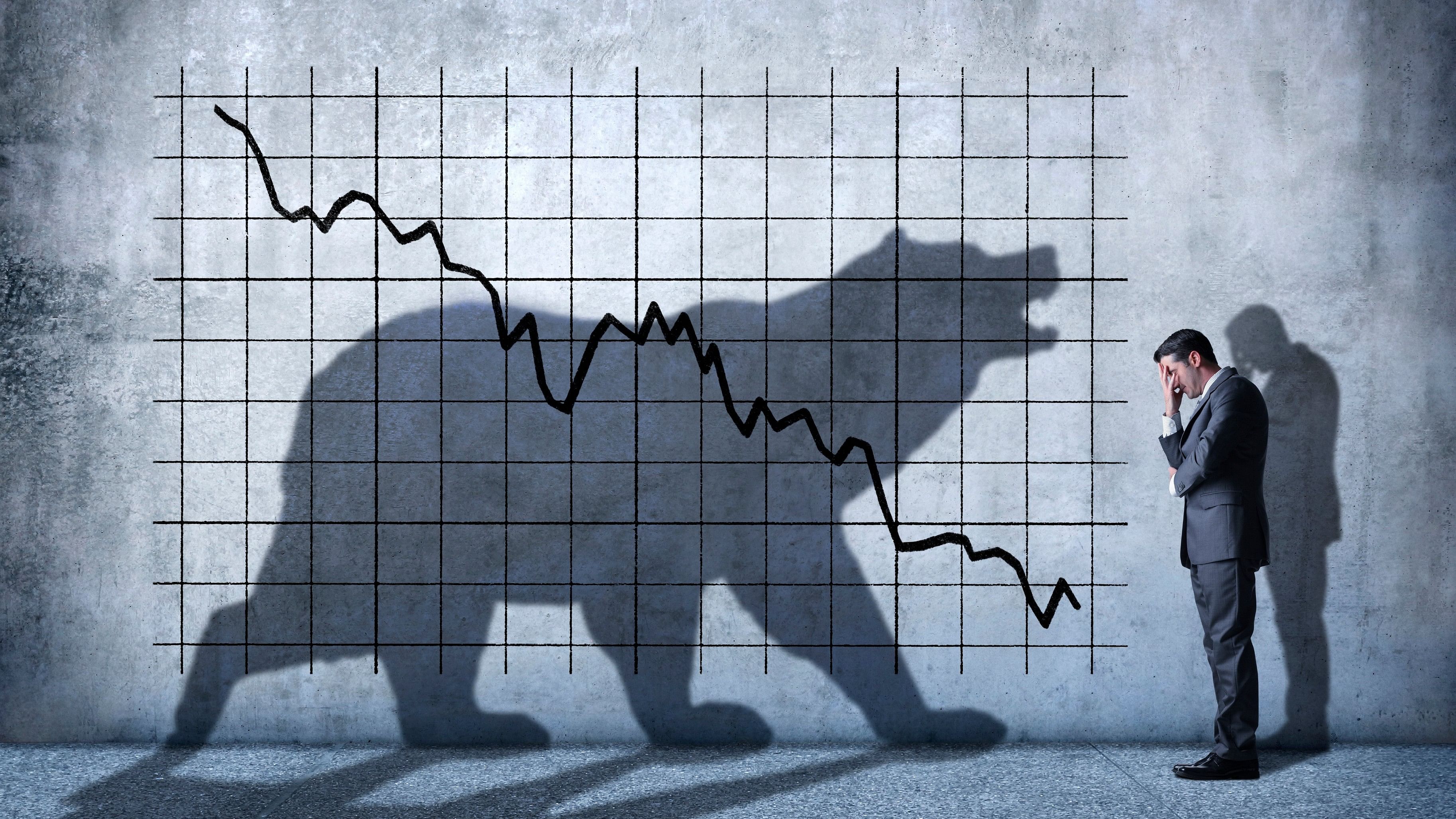 <div class="paragraphs"><p>A businessman covers his eyes as he can't watch a descending stock chart and an ominous shadow of a bear that is cast on the wall above him. </p></div>