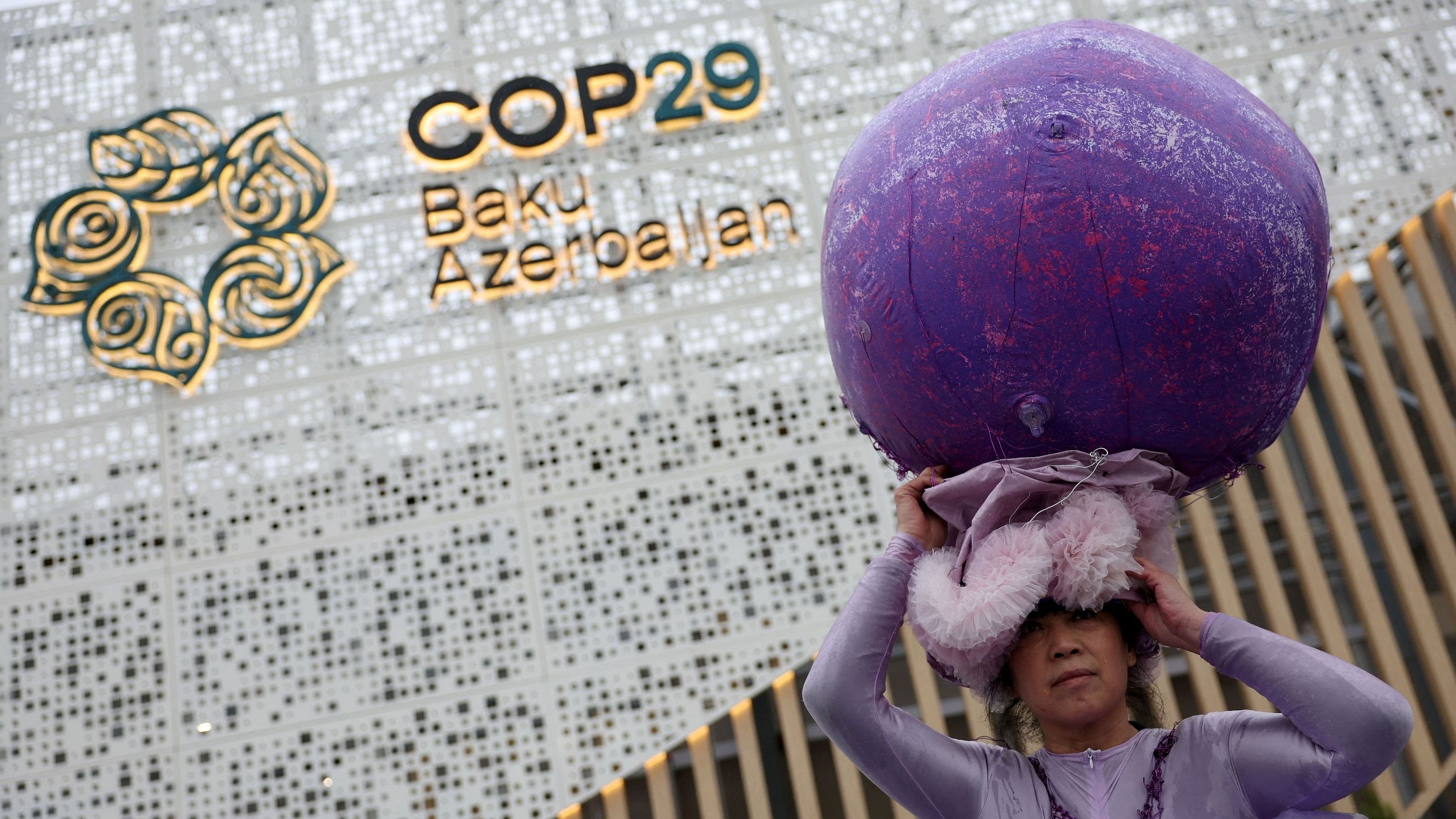 <div class="paragraphs"><p>Chinese artist Kong Ning wearing a specially made "Purple Shells" art installation, demonstrates at the entrance of the venue during the United Nations climate change conference COP29, in Baku, Azerbaijan.&nbsp;</p></div>