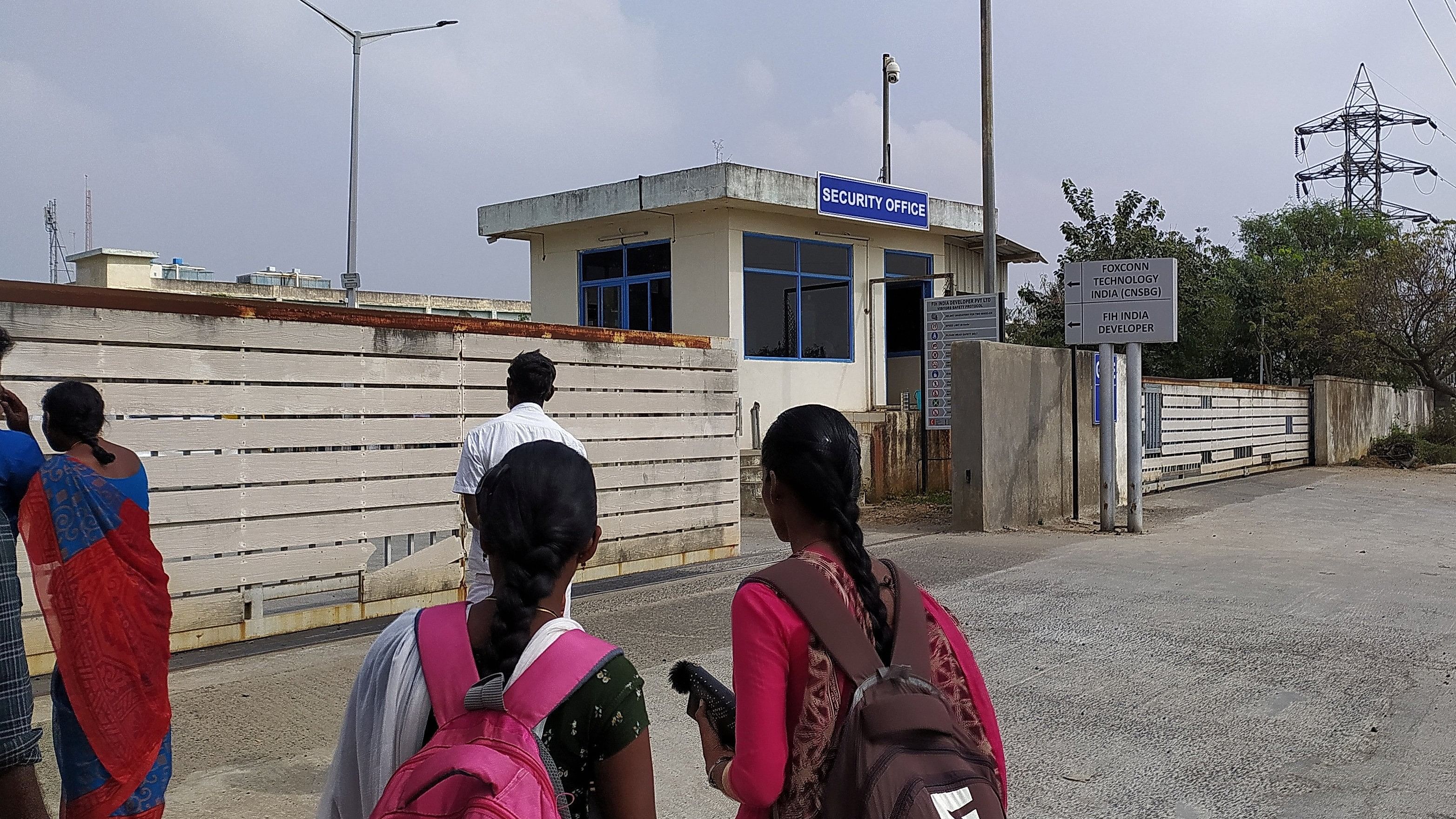 <div class="paragraphs"><p>Two unidentified women wearing backpacks stand outside a security office at the main entrance to Foxconn's factory in Sriperumbudur, near Chennai, where workers assemble iPhones for Apple.</p></div>