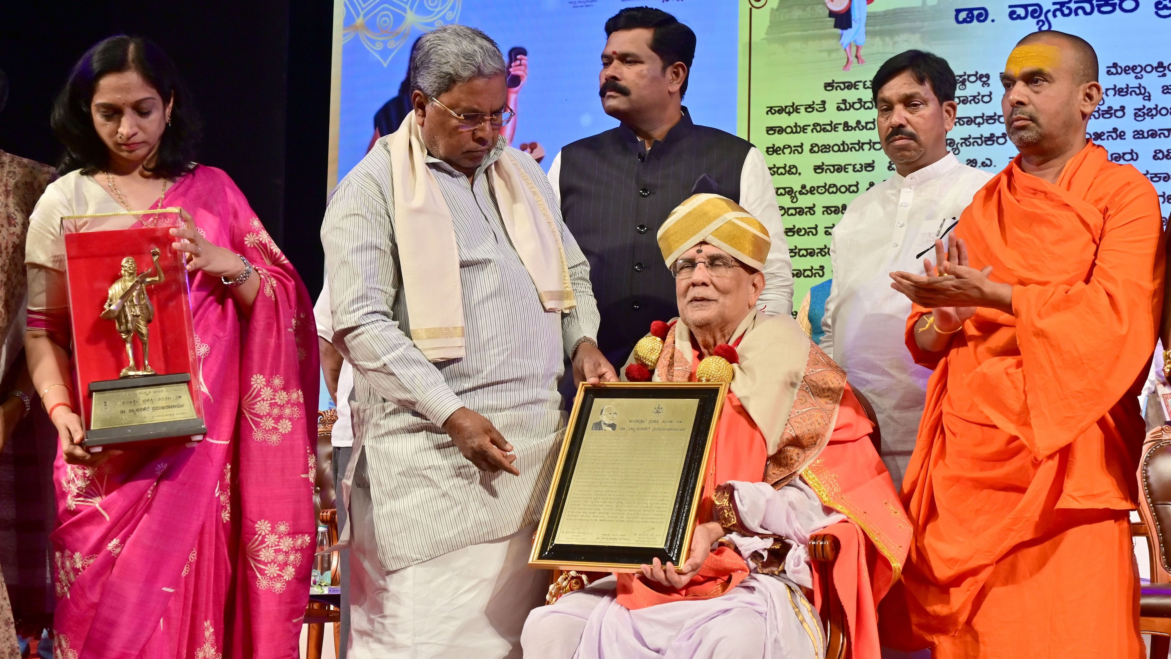 <div class="paragraphs"><p>Chief Minister Siddaramaiah confers the Kanakashri award on Sanskrit scholar Vyasanakere Prabhanjanacharya on the occasion of Kanakadasa Jayanti at the Ravindra Kalakshetra in Bengaluru on Monday. Kannada and Culture Minister Shivaraj Tangadagi, department secretary N Manjula, Deputy Speaker Rudrappa Lamani and seer Siddaramanandaswami were present.</p></div>