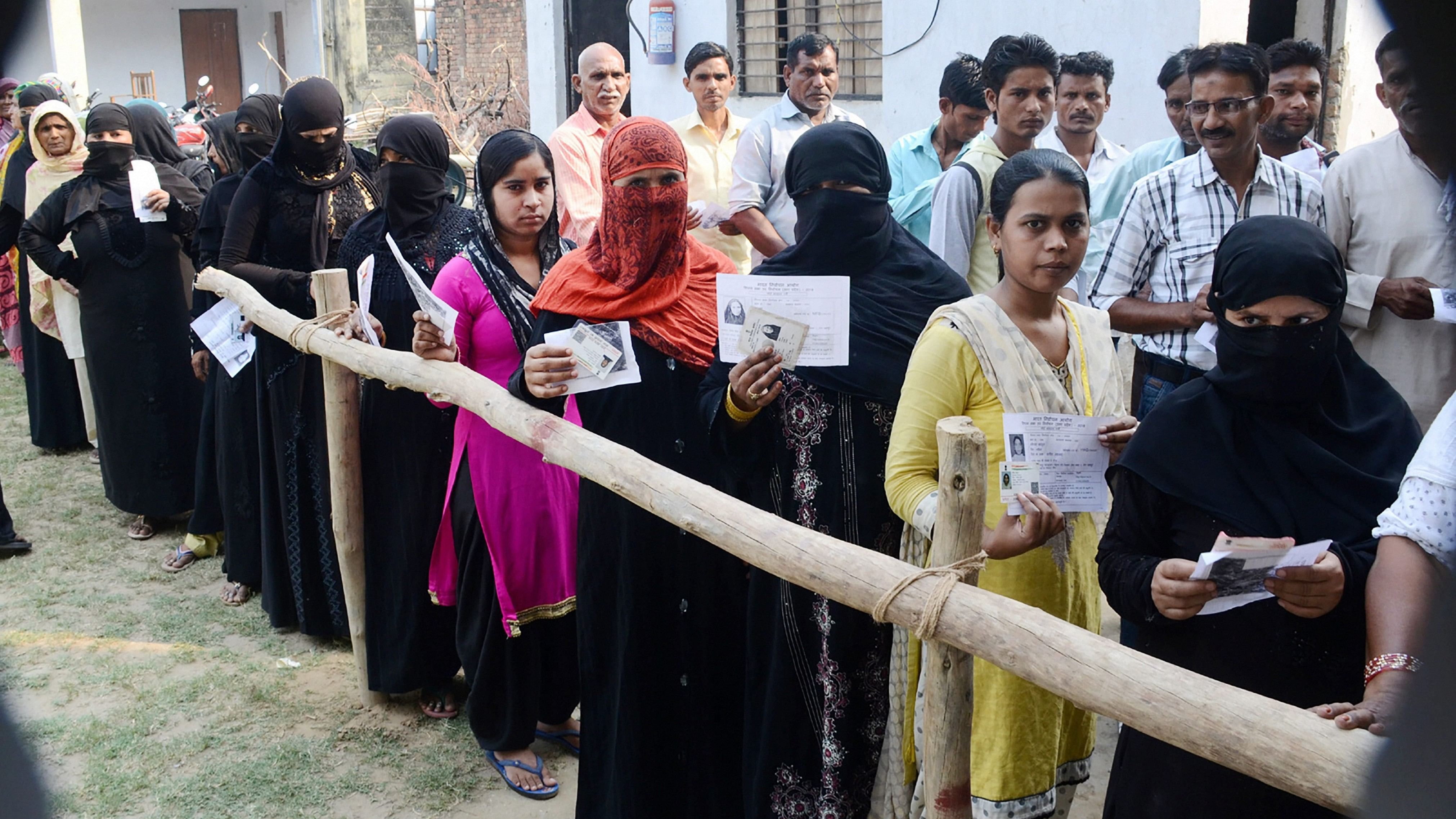 <div class="paragraphs"><p>Burqa-clad women, along with other voters, show their voter identity cards.</p></div>