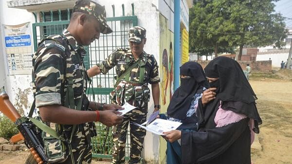 <div class="paragraphs"><p>Security personnel check identification cards of voters at a polling booth during UP's Majhawan Assembly constituency bypoll, in Mirzapur.</p></div>