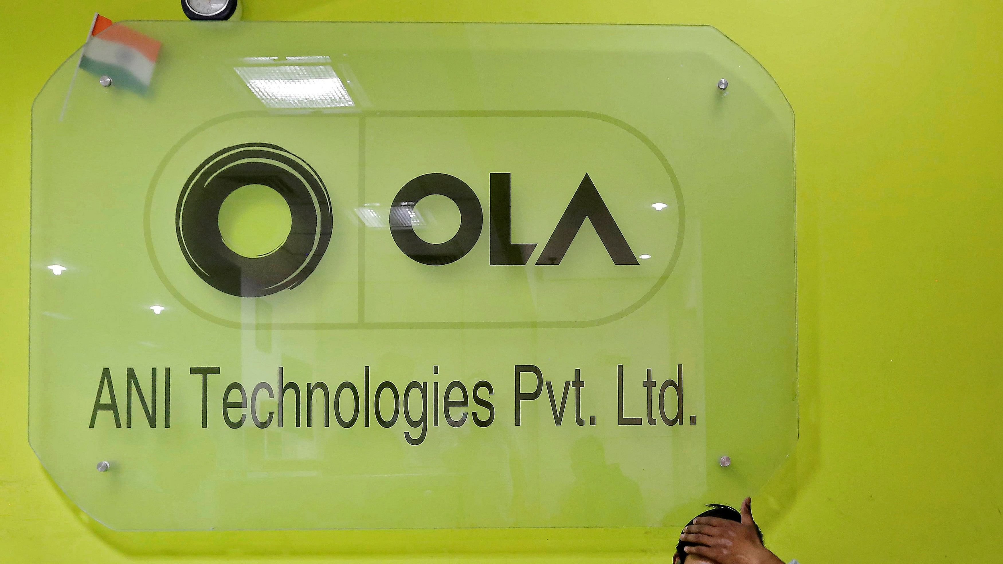 <div class="paragraphs"><p>FILE PHOTO: An employee speaks over his phone as he sits at the front desk inside the office of Ola cab service in Gurugram.</p></div>