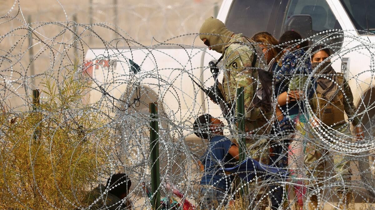 <div class="paragraphs"><p>Migrants seeking asylum try to cross a razor wire fence into the United States.</p></div>