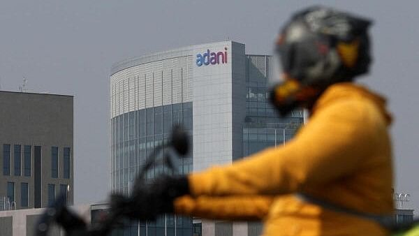 <div class="paragraphs"><p>A man rides his motorbike past the Corporate House of Adani Group on the outskirts of Ahmedabad</p></div>