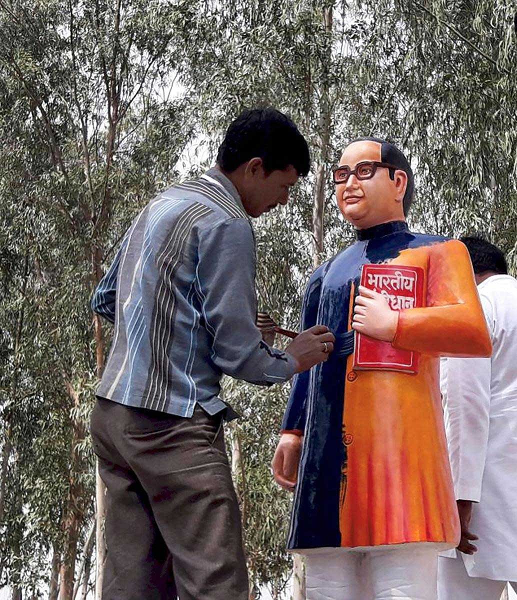 A BSP worker paints the newly constructed statue of BR Ambedkar in blue in Badaun on Tuesday. The saffron-statue raised controversy as Ambedkar's statues have always been shown in blue coat. PTI Photo 