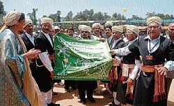 The family members of Maneyapanda receiving the flag from the Kodava Hockey Academy Founder President Pandanda Kuttappa to host the hockey tournament