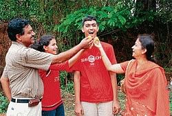 Sweet Victory: CET Engineering First rank holder Naveen Bhat being offered sweets by the members of his family. Dh photo