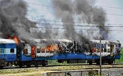 UP IN FLAMES: A train, which was set alight by followers of Guru Ravi Dass, burns near a railway station in Jalandhar on Monday. AFP