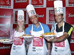 Maurice Greene with athlete Inna Lebedeva(L) and Milind Soman, display pasta cooked by them on the eve of Sunfeast World 10K run in Bangalore.AP