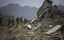 Pakistani secuirty forces officers walk over debris of houses in Sultanwas, Buner, Pakistan.