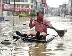 A man wades through the flooded street in a home-made raft in Cangnan, east China's Zhejiang province, on Monday. Xinhua