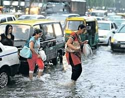 Pedestrians cross a flooded road during a sudden downpour in New Delhi on Friday. AFP
