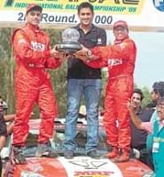Team MRFs Arjun Balu (left) and Sujith Kumar receive the trophy from Indian skipper Mahendra Singh Dhoni  after winning the K-1000 rally on Sunday.