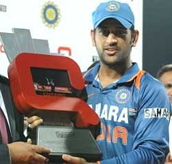 Indian captain Mahendra Singh Dhoni holds the trophy after winning the Tri-Nation Championship final. AFP