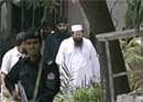 Hafiz Mohammed Saeed (C, white dress), chief of Islamic charity JuD,  seen with his aids and a police officer. AP